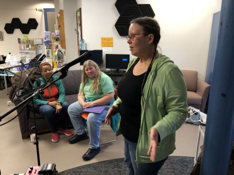 Person standing at microphone with a small audience