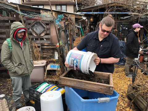 Two people filtering compost.